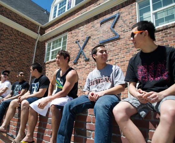 fraternity members hanging out in front of house
